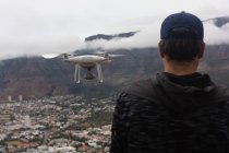 Vista trasera del hombre operando un dron volador - foto de stock
