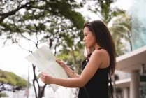 Beautiful woman looking at map in city street — Stock Photo