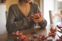 Sezione centrale della donna che mostra origami a casa — Foto stock