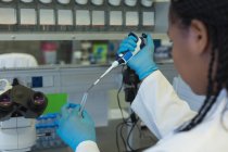Wissenschaftler pipettiert Lösung im Labor ins gläserne Reagenzglas — Stockfoto