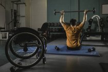 Rear view of handicapped man exercising with barbell in gym — Stock Photo