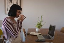 Молода жінка має каву вдома — стокове фото