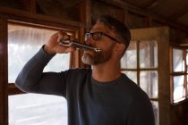 Gros plan d'un homme buvant du whisky dans une cabane en rondins — Photo de stock