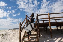 Coppia di surfisti che passeggia in spiaggia in una giornata di sole — Foto stock