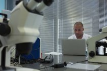 Científico usando portátil en el escritorio en el laboratorio de ciencias - foto de stock