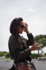 Beautiful woman in sunglasses using mobile phone on street — Stock Photo