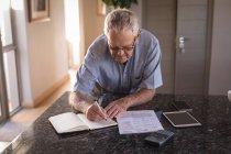 Активний старший чоловік пише на щоденнику вдома — стокове фото