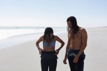 Серферская пара взаимодействует друг с другом на пляже — стоковое фото