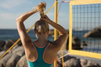Jogadora de voleibol feminina ajustando o cabelo na praia — Fotografia de Stock