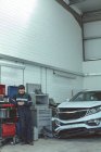 Mechaniker mit Handy bei Reparatur in der Garage — Stockfoto