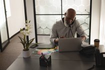 Старший графический дизайнер разговаривает по мобильному телефону за столом в офисе — стоковое фото