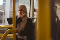 Hermosa mujer hijab utilizando tableta digital en el autobús - foto de stock