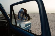 Casal de romances em um capô de caminhão de coleta na praia — Fotografia de Stock