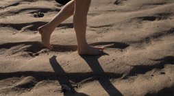 Baixa seção de mulher andando na areia na praia — Fotografia de Stock