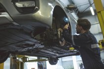 Чоловічий механізм вивчення автомобіля з факелом в ремонтному гаражі — стокове фото