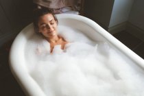 Woman taking a bubble bath in bathroom at home — Stock Photo