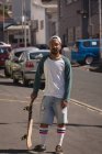 Retrato del hombre de pie con monopatín en la calle - foto de stock