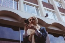 Visão de baixo ângulo da bela mulher hijab usando telefone celular — Fotografia de Stock