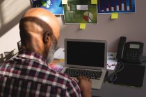 Senior graphic designer using laptop at desk in office — Stock Photo
