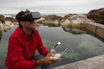 Человек, управляющий летающим дроном, используя гарнитуру виртуальной реальности в сельской местности — стоковое фото