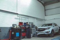 Meccanico utilizzando il telefono cellulare durante la riparazione di auto in garage — Foto stock