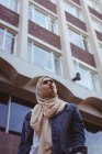 Visão de baixo ângulo da mulher hijab em pé contra a construção — Fotografia de Stock