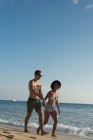 Casal caminhando juntos de mãos dadas na praia — Fotografia de Stock