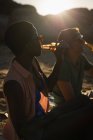 Zwei Freunde trinken in der Abenddämmerung Bier am Strand — Stockfoto