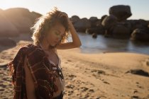 Продумана жінка стоїть на пляжі в сонячний день — стокове фото