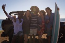 Группа друзей делает селфи с мобильным телефоном на пляже — стоковое фото