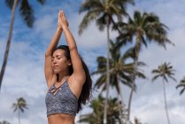 Femme effectuant du yoga à la plage par une journée ensoleillée — Photo de stock