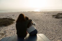 Вид сзади на отдыхающую пару на капоте пикапа на пляже — стоковое фото