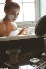 Frau cremt sich mit Feuchtigkeitscreme ein, während sie zu Hause im Badezimmer badet — Stockfoto