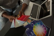 Мужской графический дизайнер смотрит на цветные образцы в офисе — стоковое фото