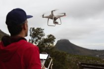 Вид сзади на человека, управляющего летающим дроном в сельской местности — стоковое фото