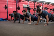 Vue latérale des athlètes faisant pousser vers le haut dans la salle de gym — Photo de stock