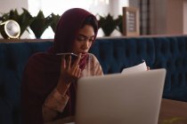 Деловая женщина в хиджабе разговаривает по мобильному телефону в офисной столовой — стоковое фото