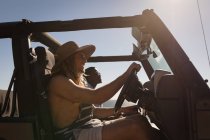 Amigos conduciendo jeep en la playa en un día soleado - foto de stock
