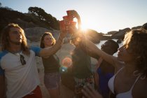 Група друзів розважаються на пляжі в сутінках — стокове фото