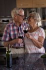 Coppia anziana brindisi bicchieri di vino in cucina a casa — Foto stock
