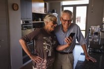 Senior couple appel vidéo sur téléphone portable dans la cuisine à la maison — Photo de stock