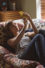 Bella donna che prende selfie sul divano in soggiorno a casa — Foto stock
