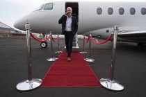Uomo d'affari che parla sul cellulare mentre lascia jet privato al terminal — Foto stock