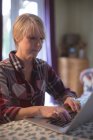 Mujer madura usando el ordenador portátil en la sala de estar en casa - foto de stock
