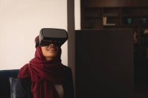 Femme d'affaires dans le hijab en utilisant le casque de réalité virtuelle à la cafétéria de bureau — Photo de stock