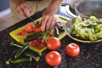 Seção média do homem sênior cortando legumes na cozinha em casa — Fotografia de Stock