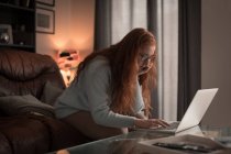 Mulher usando laptop na sala de estar em casa — Fotografia de Stock