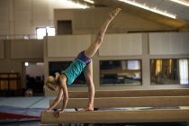Female athletic balancing on wooden bar at fitness studio — Stock Photo