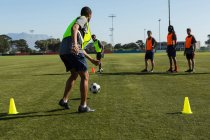 Гравці, які практикують футбол в полі в сонячний день — стокове фото