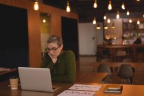 Empresária usando laptop na cafetaria no escritório — Fotografia de Stock